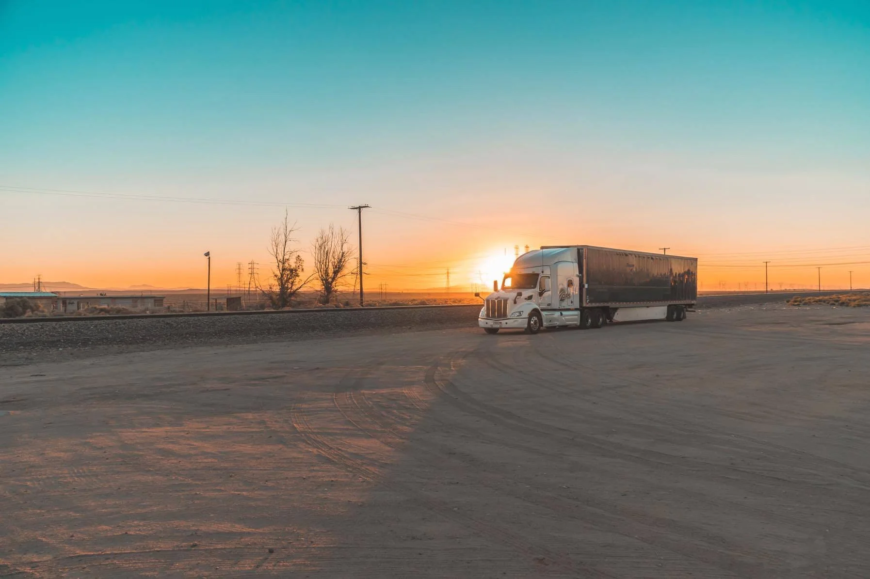 Un camión con remolque detenido en una carretera del desierto, al amanecer.