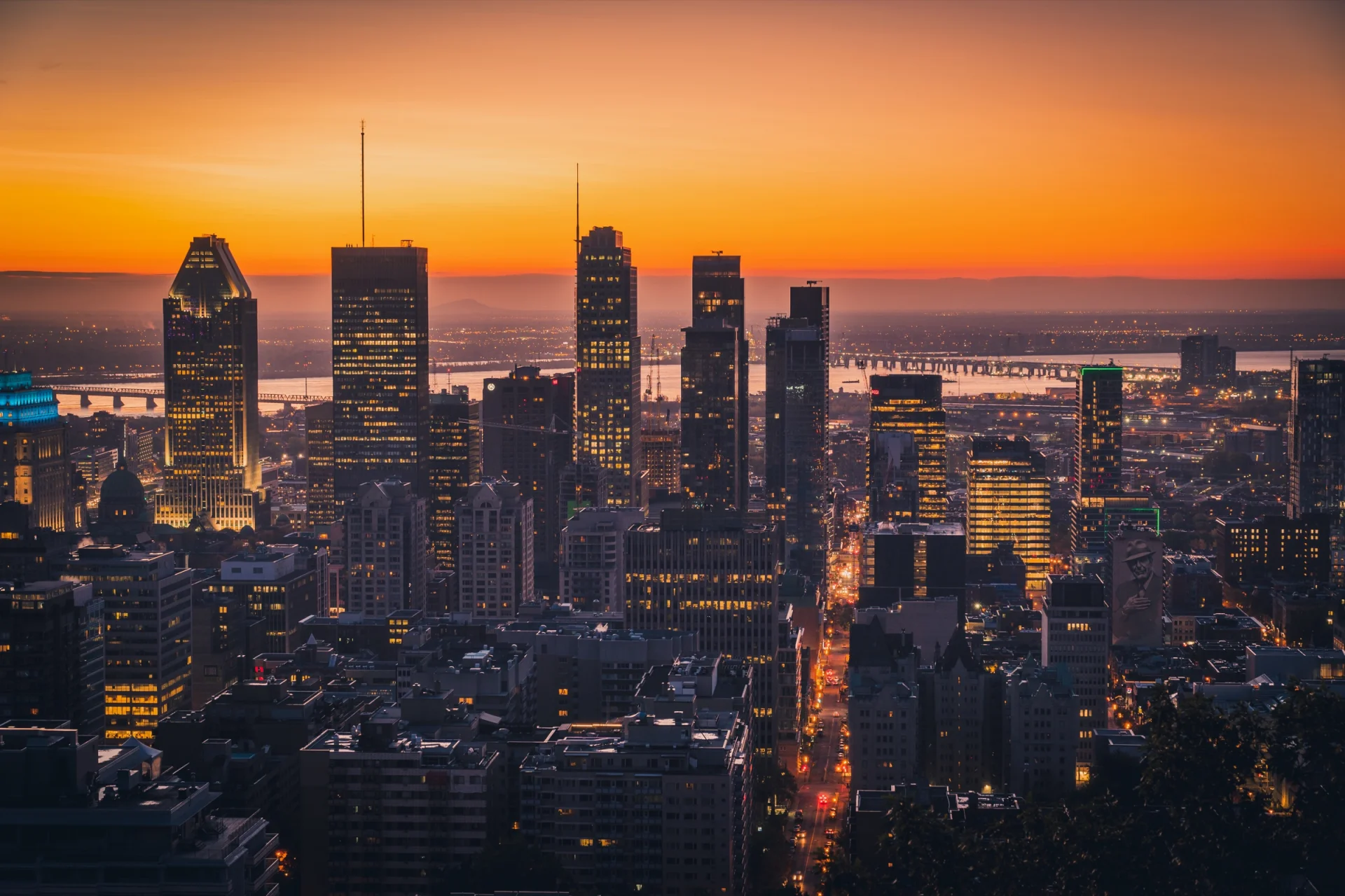 El centro de Montreal al anochecer bajo un cielo naranja, con las ventanas encendidas.