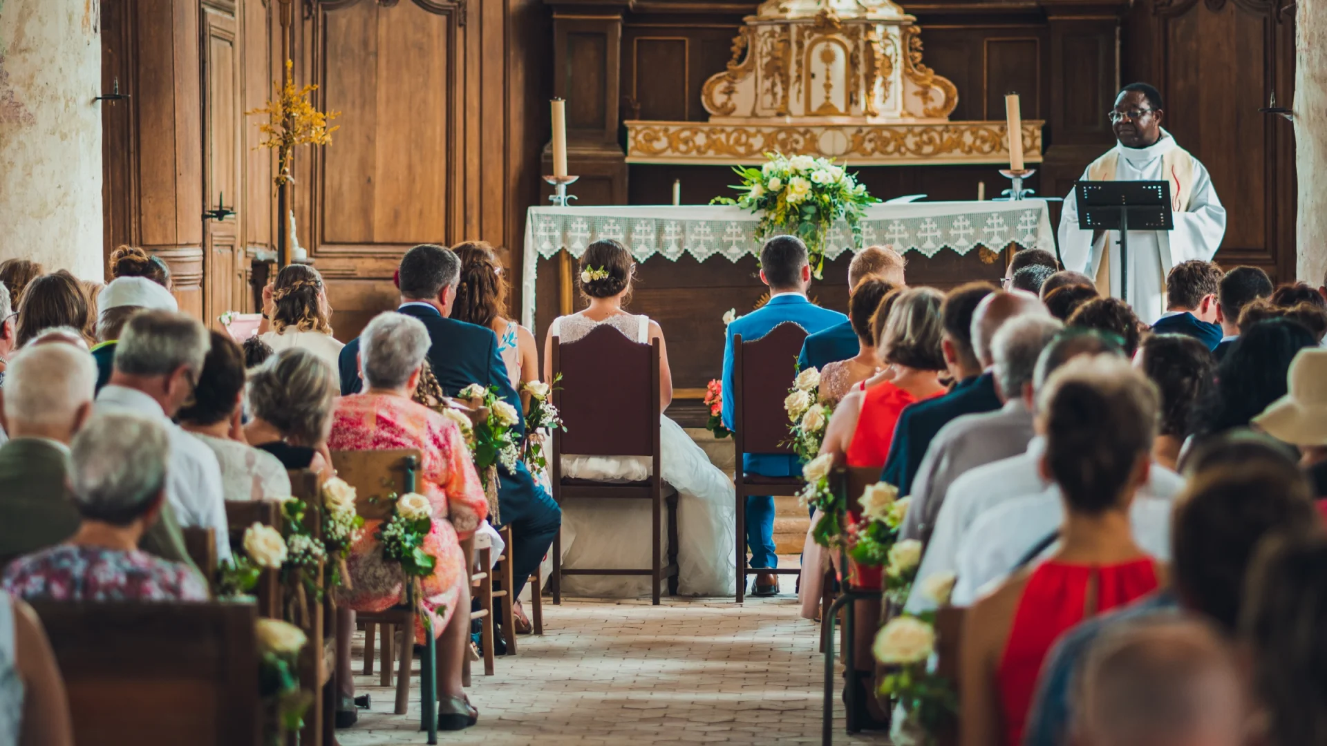 Los asistentes en una iglesia durante una ceremonia de boda, vistos desde el fondo del pasillo.