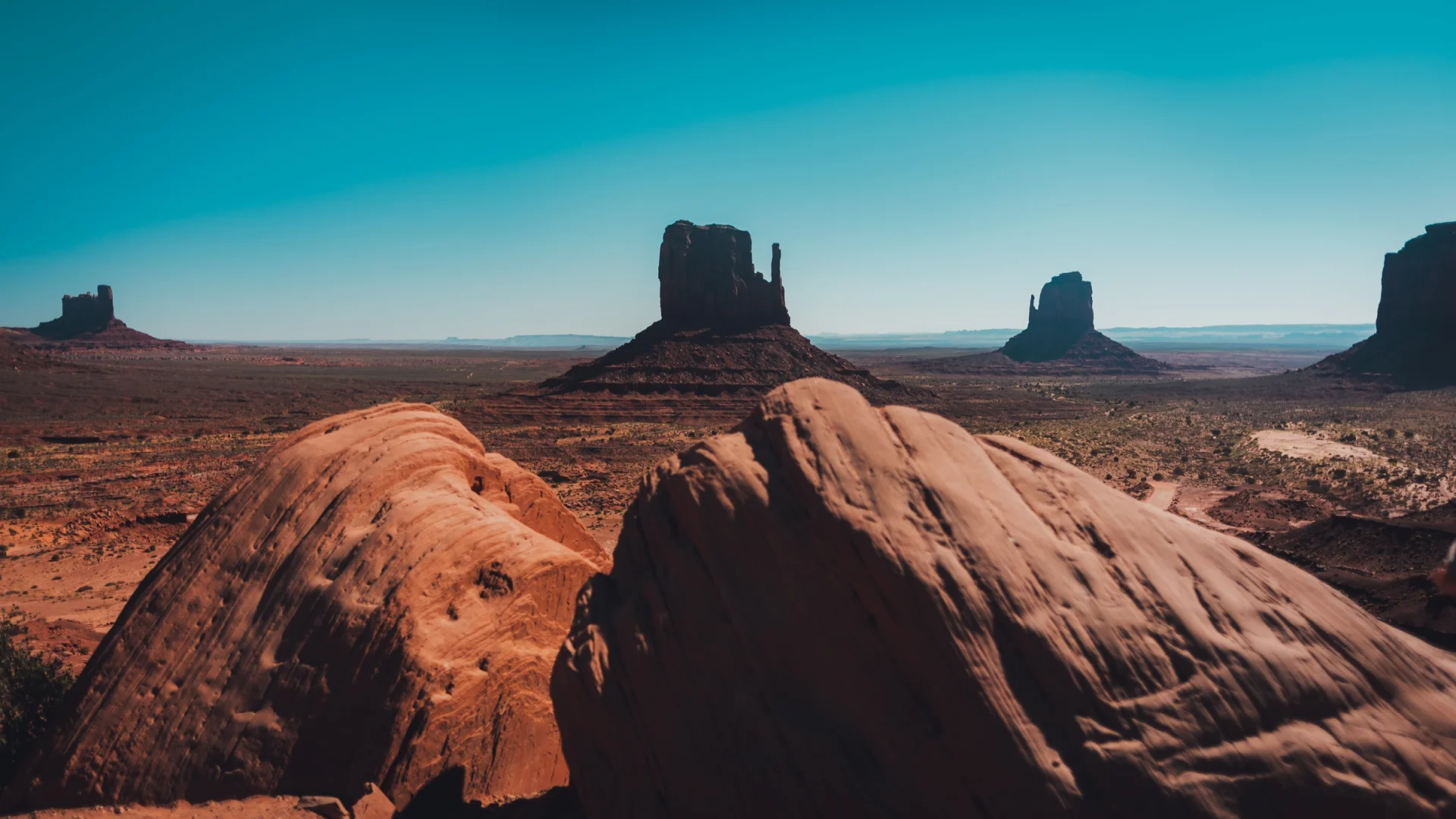 Los cerros de Monument Valley sobre rocas oscuras en primer plano.