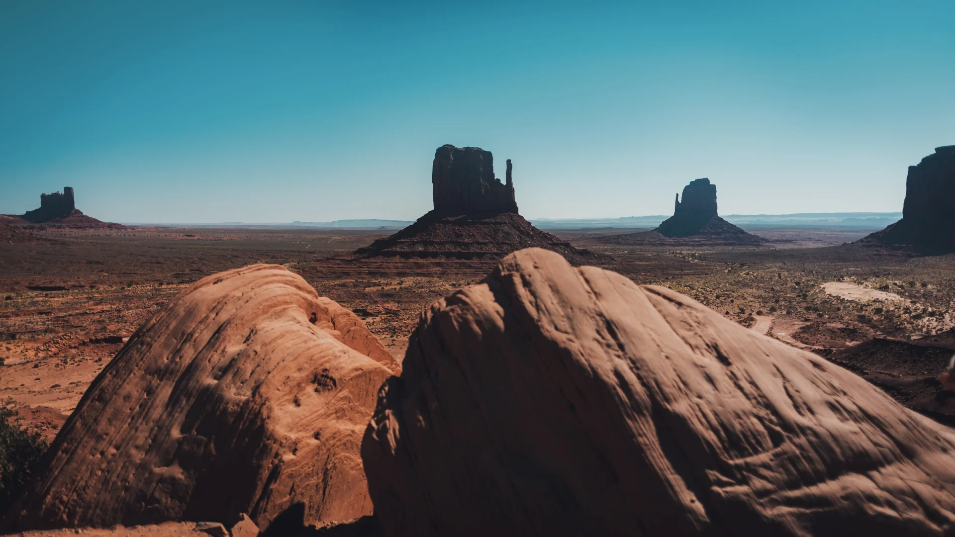 Les buttes de Monument Valley au-dessus de rochers sombres au premier plan.