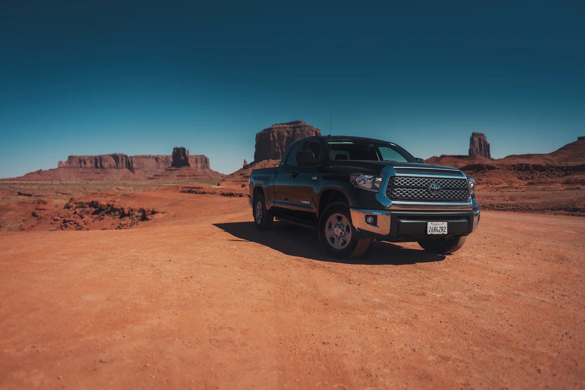 Un pick-up arrêté sur une piste de Monument Valley, les buttes à l'horizon.