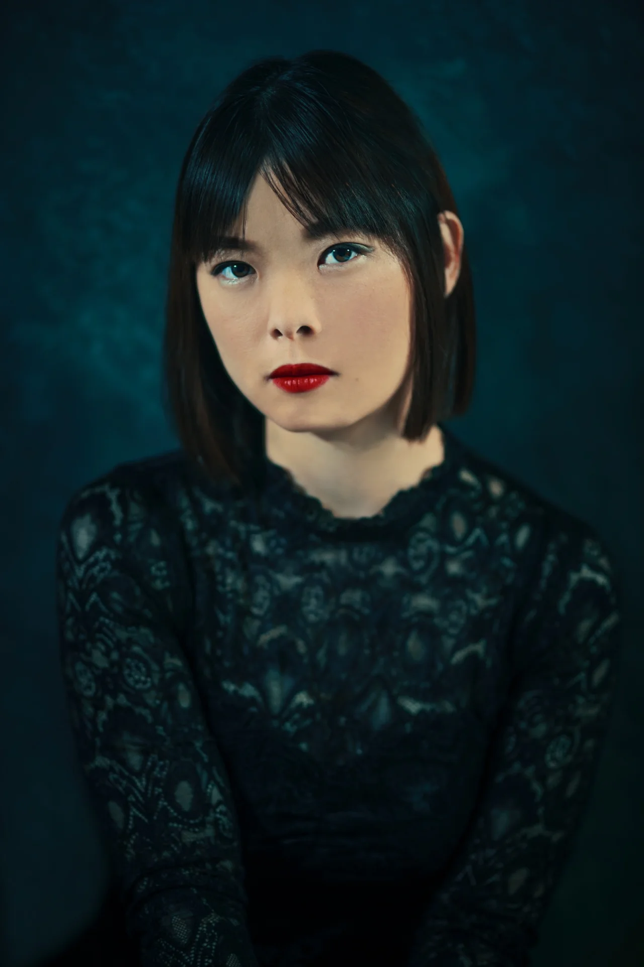Retrato de una mujer de encaje negro sobre un fondo azul oscuro.