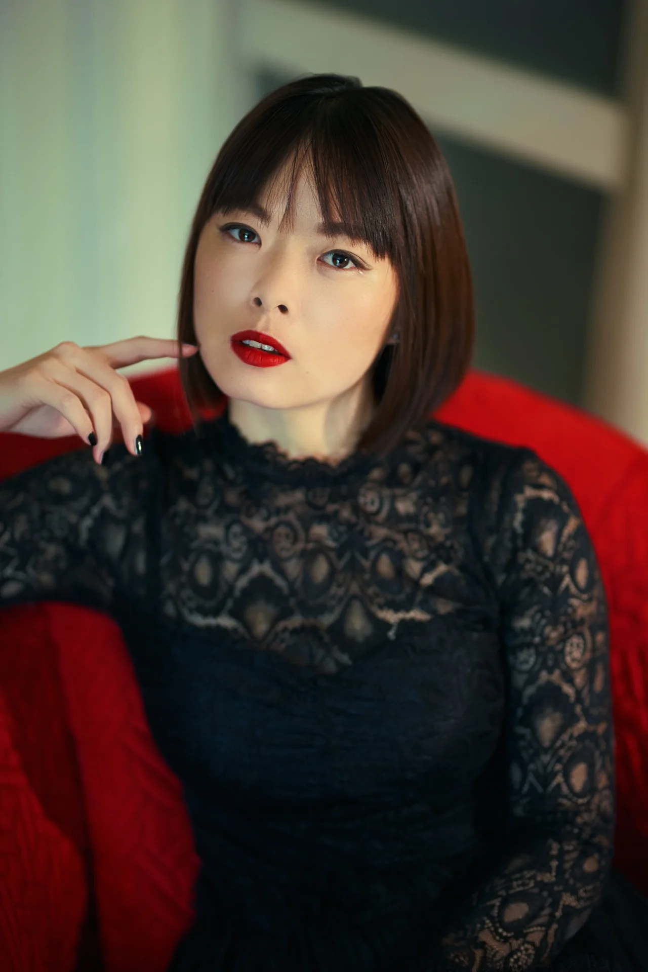 Retrato de una mujer de encaje negro, sentada en un sillón rojo.