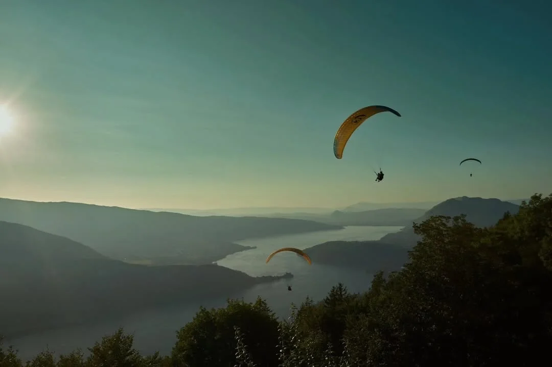 Una vela de parapente sobre el lago de Annecy, con el valle cubierto de bruma.